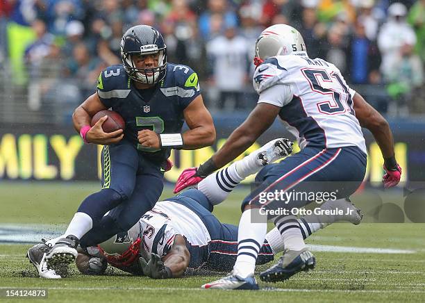 Quarterback Russell Wilson of the Seattle Seahawks rushes against defensive tackle Vince Wilfork, and outside linebacker Jerod Mayo of the New...