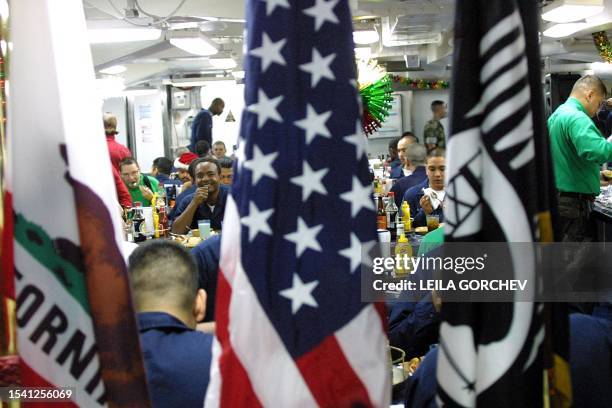 Crew members enjoy a Christmas Eve meal in the mess deck of the USS Constellation 24 December 2002 in the Gulf waters. The USS Constellation is...