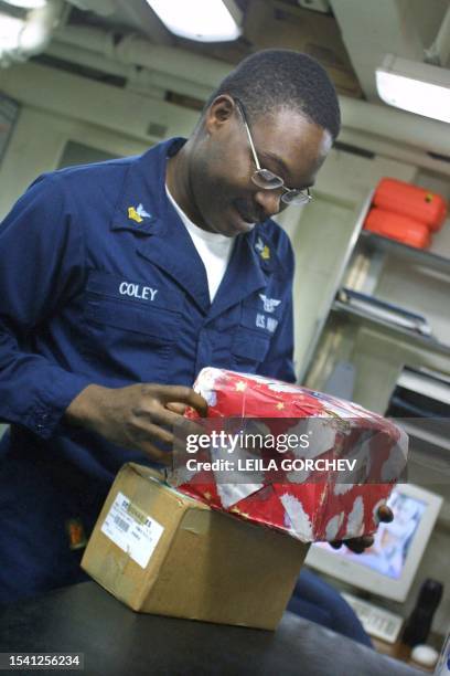 Sailor PO1 Lancelot Coley of Miami, Florida, looks at Christmas parcels he received 23 December 2002 aboard the USS Constellation in the Gulf. The...