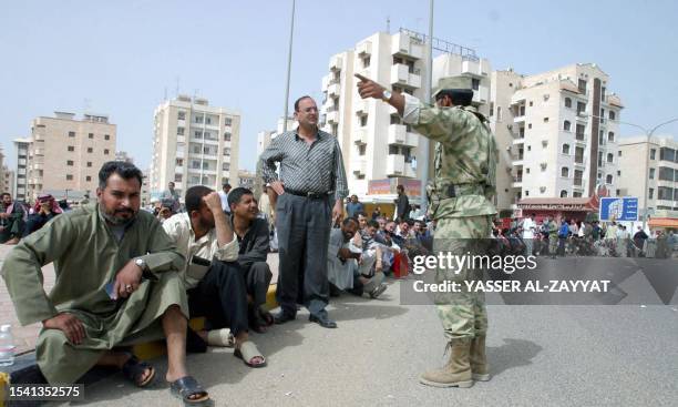 Kuwaiti soldier stands guard as hundreds of expatriates, mainly Syrians, Lebanese and Egyptians gather at the Saudi Embassy 21 March 2003 to obtain...