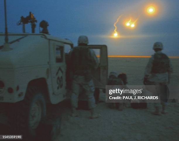 Forward Observers with the 1st Battalion, 9th Field Artillery stand silhouetted as illuminating flares fall over the target range in the pre-dawn...