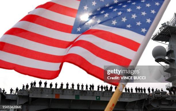 Navy sailors stabnd on the deck as they deploy with the aircraft carrier USS Nimitz from North Island Naval Station on 03 March in San Diego,...