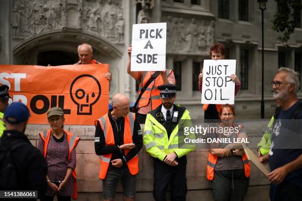 Just Stop Oil climate activists stands in handcuffs after being detained by police while marching slowly in Parliament Square on July 19, 2023....