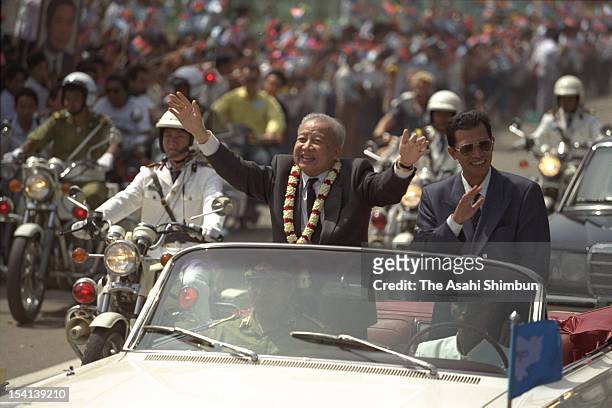 Former Cambodian King, Prince Norodom Sihanouk and Cambodian Prime Minister Hun Sen wave to audience during the welcome parade to celebrate...