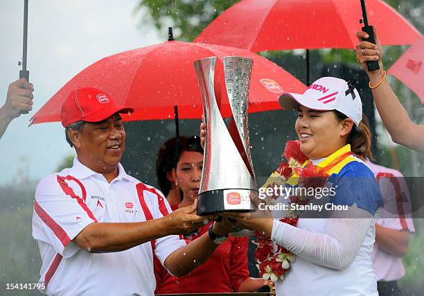 Inbee Park of South Korea receives the Sime Darby LPGA Trophy from the Deputy Prime Minister of Malaysia Tan Sri Muhyiddin Yassin under the rain...