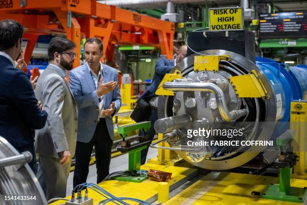 Chilean President Gabriel Boric listens to explanations from Large Hadron Collider operator Mirko Pojer , standing next to a giant magnet during...