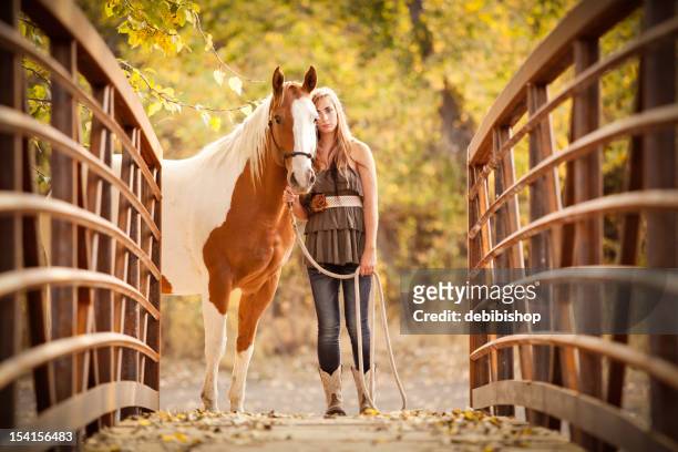 long haired teen girl standing with her horse on bridge - autumn steed stock pictures, royalty-free photos & images