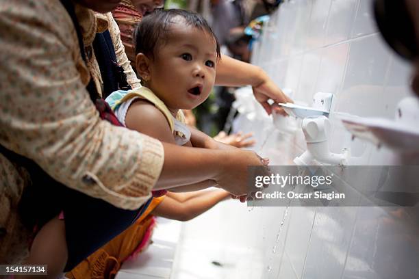 Mother help her baby to wash her hands on Global Handwashing Day on October 15, 2012 in Jakarta, Indonesia. Celebrated in over 100 countries, Global...