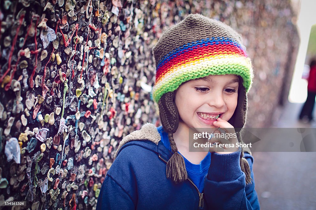 Boy chewing gum next to wall of bubblegum