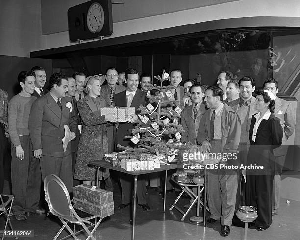 Blondie" cast Christmas party. Penny Singleton as 'Blondie'and Arthur Lake holding a package with producer Tom McKnight behind them admiring...