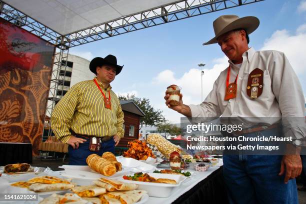 Rick Harsch holds Bum's Blue Ribbon Pulled Pork Sundae as Jay Justilian looks on while organizing entered food during the 3rd Annual Gold Buckle...