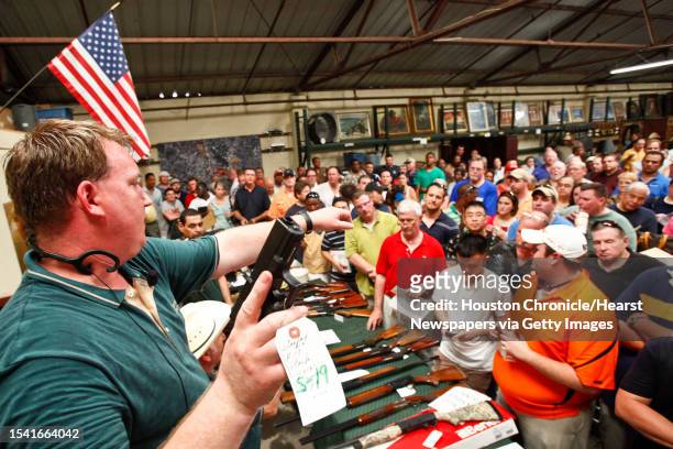 Eric Worstell holds up a Glock 19 9mm as he auctions off thousands of items seized from disgraced financier R. Allen Stanford's Houston offices, at...