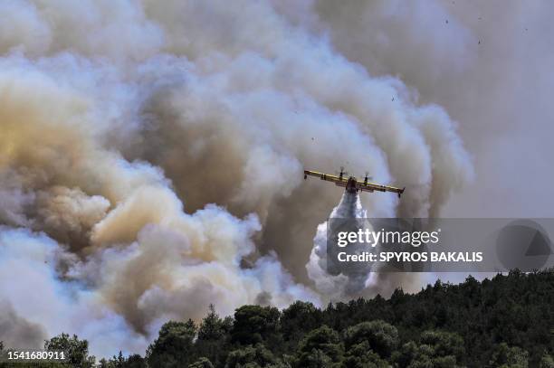 Canadair firefighting plane sprays water during a fire in Dervenochoria, north-west of Athens, on July 19, 2023. Extreme heat was forecast across the...