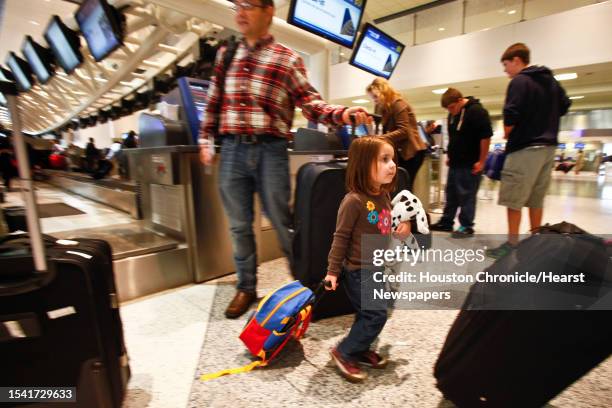 Erin Pilicer carries her luggage as her father Nihat checks-in their baggage before traveling to Virginia for the Thanksgiving holiday at Terminal C...