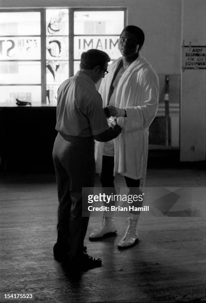 American boxing coach Angelo Dundee tapes the hand of heavyweight boxer Muhammad Ali during training at the 5th Street Gym, Miami, Florida, 1971. Ali...