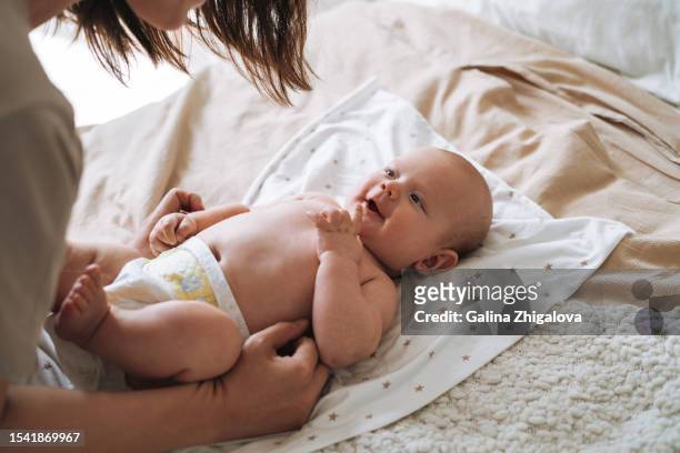 adult woman young mother with 2-3 month baby boy lying on white blanket at home - diapers stockfoto's en -beelden