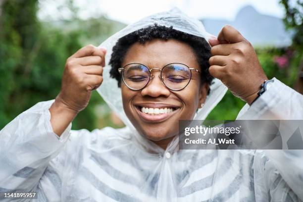 雨の中で外でレインコートを着た幸せな若いブラジル人女性 - レインコート ストックフォトと画像