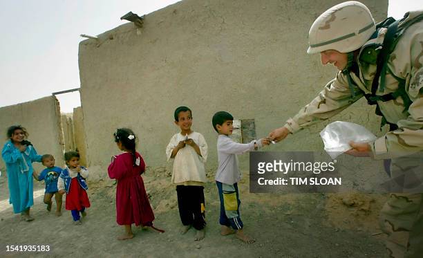 Young children accept candy from Sgt. David Marr of Syracuse, New York, of the US Army Civil Affairs Unit, during a visit local to a local village...
