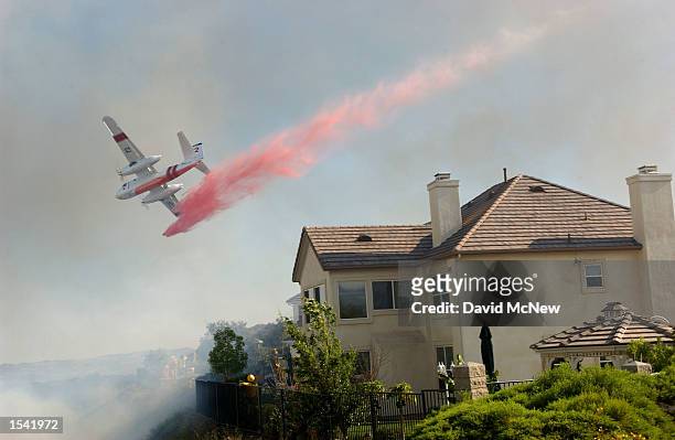 An air tanker drops fire retardant on homes threatened by wildfire in the gated community of Coto de Caza May 13, 2002 near Rancho Santa Margarita,...
