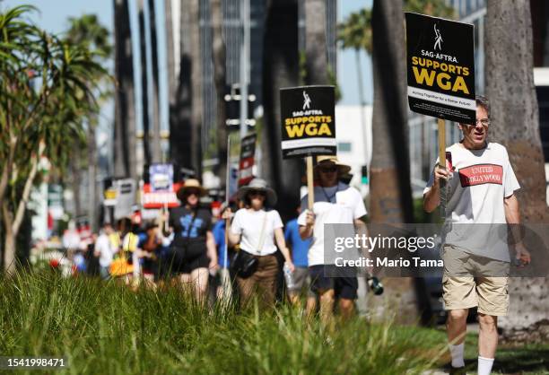 Sign reads 'SAG-AFTRA Supports WGA' as SAG-AFTRA members walk the picket line on Day 1 in solidarity with striking WGA workers outside Netflix...