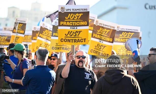 Workers hold placards at a rally held by the Teamsters Union on July 19, 2023 in Los Angeles, California, ahead of an August 1st deadline for an...