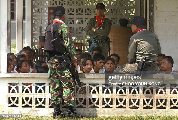 Indonesian government troops guard detained Acehnese civilians as Indonesian troops sweep the area for GAM rebels , at Pantai Baru, 10 Km from...