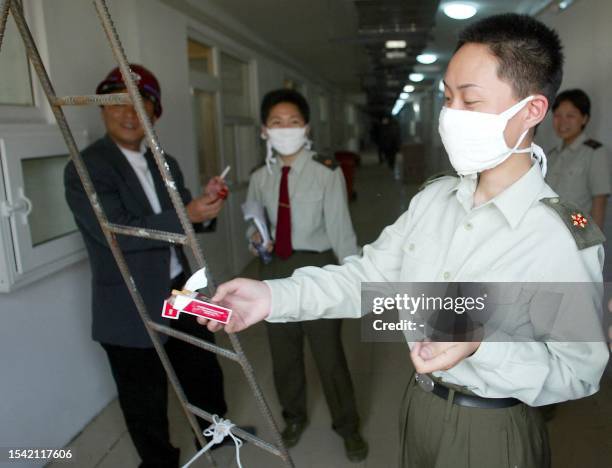 Chinese People's Liberation Army medical staff offers cigarettes to workers at the hospital erected in barely a week to house a rapidly increasing...