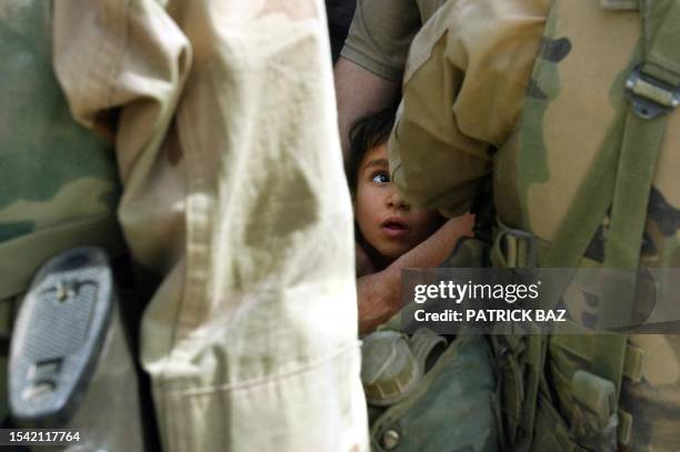 An Iraqi boy reacts as he is squeezed between US Marines and Iraqi protesters in front of Baghdad's Palestine Hotel 12 April, 2003. Dozens of Iraqis...