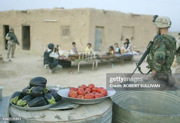 Members of the 4th Infantry Division, 1st Brigade Combat Team 42 Field Artillery keeps watch over a family 31 August 2003 during an early morning...