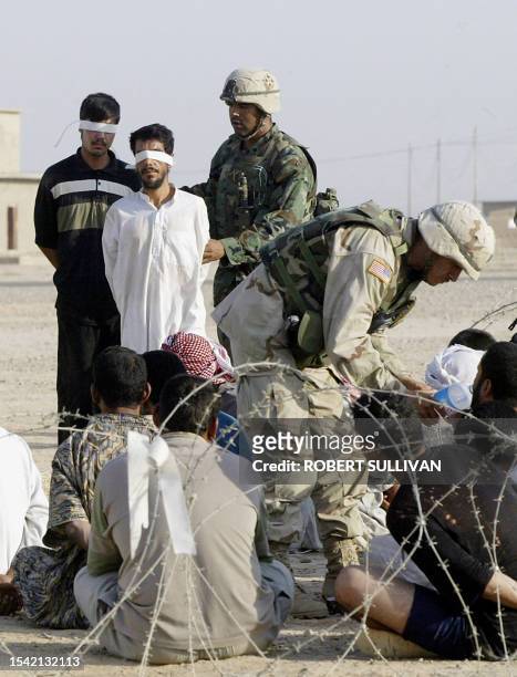 Members of the 4th Infantry Division, 1st Brigade Combat Team 42 Field Artillery round up detainees for questioning 31 August 2003 during an early...