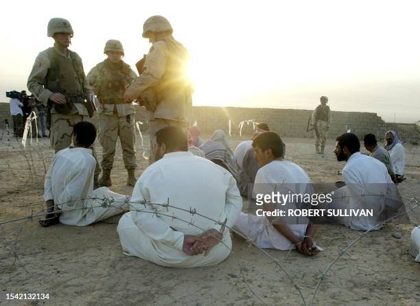 Members of the 4th Infantry Division, 1st Brigade Combat Team 42 Field Artillery keeps watch over detaines 31 August 2003 during an early morning...