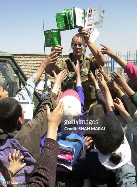 German International Security Assistance Force soldier distributes flags promoting good health to school children in Kabul, 22 April 2003. In August,...