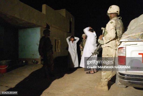 Soldiers of the 4th ID, 3rd Battalion, 66th armoured regiment detain two Iraqi men during a predawn raid 04 August 2003 at the house of Hussein Hawas...