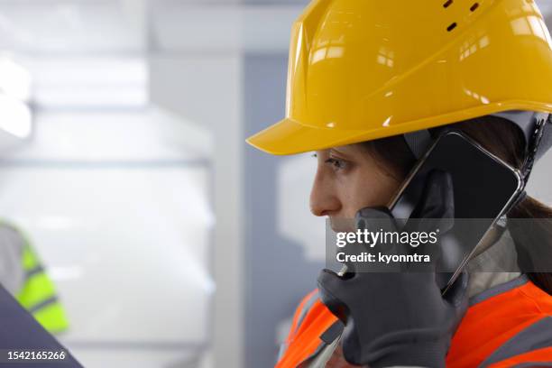 female worker in the critical infrastructure industry talking into a mobile phone - wind tunnel testing 個照片及圖片檔