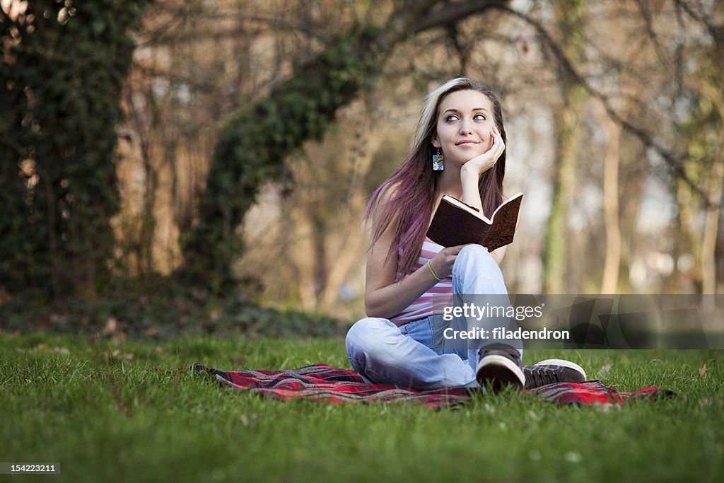 Beautiful girl reading a book and relax in the park