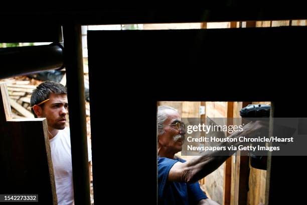 Dan Phillips and Jared Gamble hang a home-made door under the back porch of the Bone House, a two-bedroom home plus studio, made out of recycled and...