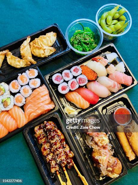 top view of quality sushi and sashimi set takeaway with japanese side dishes on table laid with tablecloth - foodstyling stockfoto's en -beelden