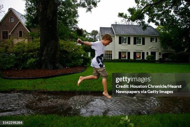 Ewan Curtis splashes in a puddle of water during a rainy afternoon in Houston Saturday, April 18 in Houston.