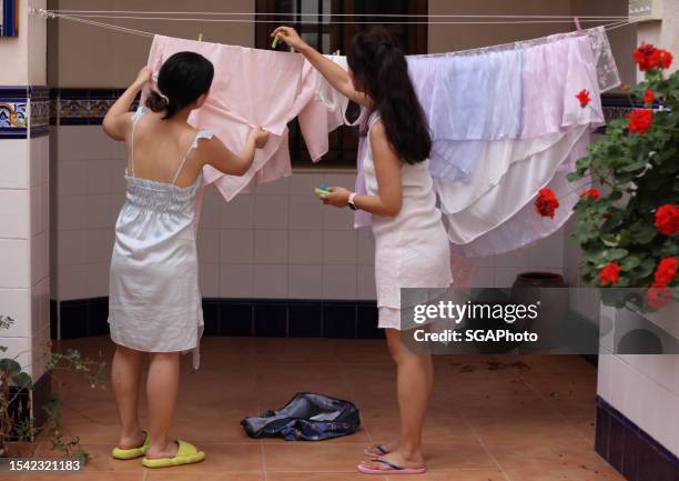 chinese girls handling washing line with clothes - nightdress stock pictures, royalty-free photos & images