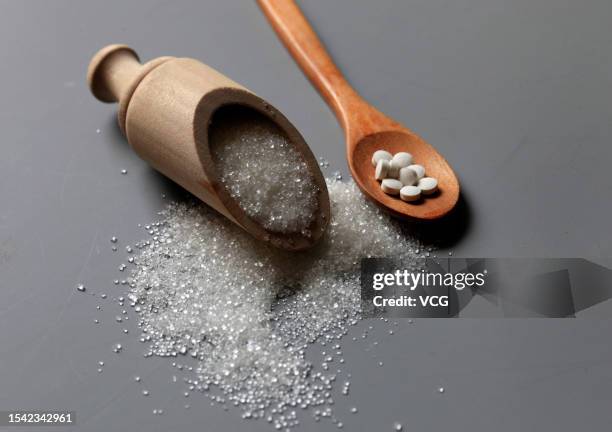 In this photo illustration, a spoonful of aspartame tablets, artificial sweetener, lies next to sugar on July 10, 2023 in Shijiazhuang, Hebei...