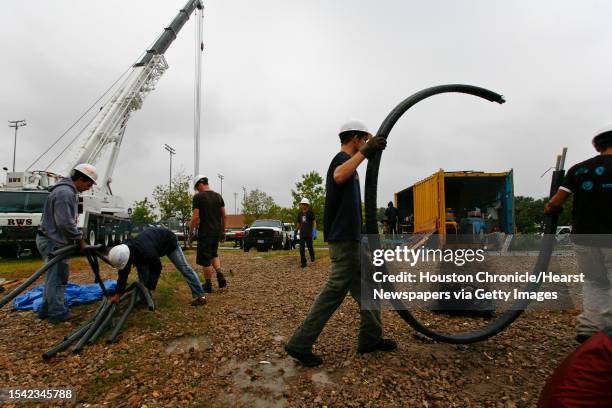 Rice University students, Charles Sharpless and Jesse Yang carry a piece of tubing to help clean up the construction sight where a 20-ton house named...