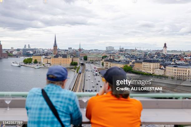 People have drinks at a rooftop bar as they watch the skyline of the city in Stockholm, on July 19, 2023. / Sweden OUT