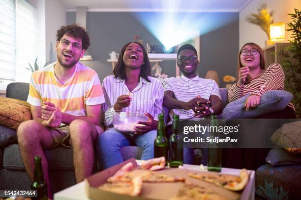 cheerful group of multiracial friends watching a movie - cinema projector stock pictures, royalty-free photos & images