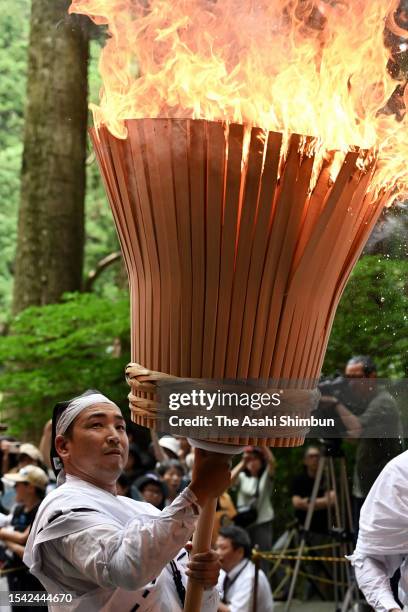 Shrine parishioners hold big flaming torches to purify the path for portable shrines during Kumano Nachi Fire Festival on July 14, 2023 in...