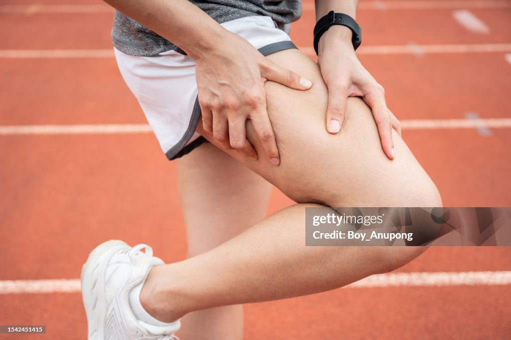 Cropped shot of female runner having thigh pain after running in the running track.