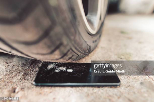 demolished mobilephone under a car tire. - broken phone stock pictures, royalty-free photos & images