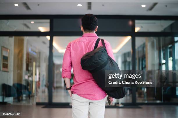 guapo hombre de negocios entrando en el hotel. - llevar al hombro fotografías e imágenes de stock
