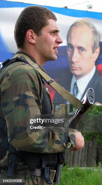South Ossetian soldier stands near the poster of Russian President Vladimir Putin in Tkviavi, South Ossetia, 01 June 2004. Georgia moved some 400...