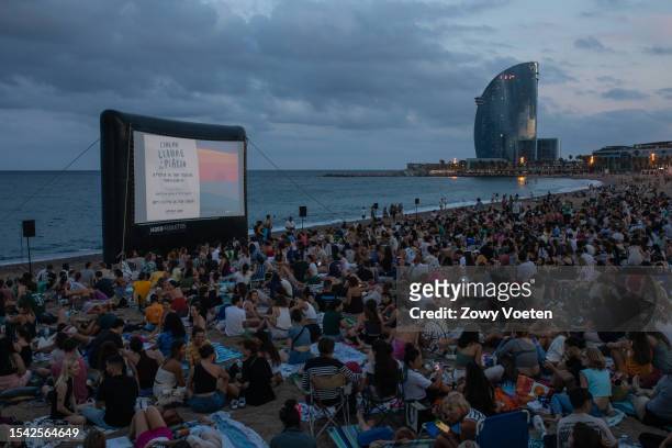 People enjoy an outdoor cinema on the Barceloneta beach at dusk, as it is a way to withstand the heat of the city on July 13, 2023 in Barcelona,...