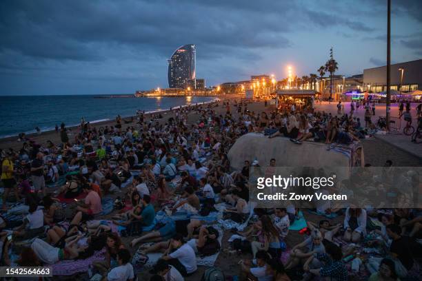 People enjoy an outdoor cinema on the Barceloneta beach at dusk, as it is a way to withstand the heat of the city on July 13, 2023 in Barcelona,...